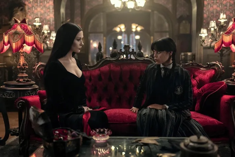 Image extrait de Wednesday avec Morticia et Wednesday assises en face l'une de l'autre sur un divan